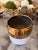 Contemporary ceramic planter/cachepot featuring a white body accented by a reflective metallic gold wide upper band. A...