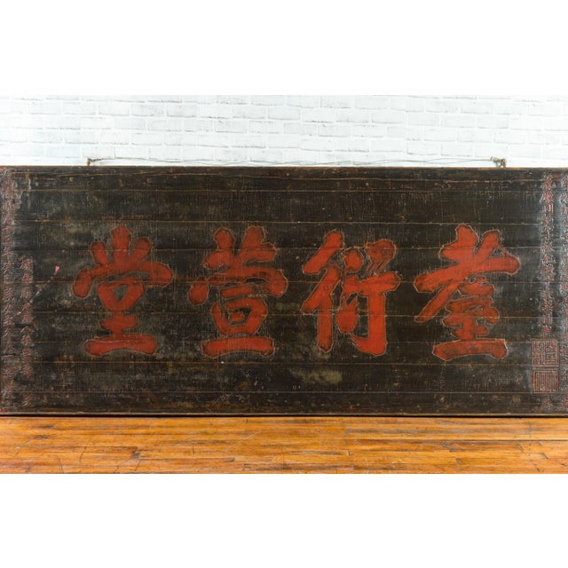 A large Chinese Qing Dynasty period black signboard from the 19th century, with red calligraphy. Created during the Qing...