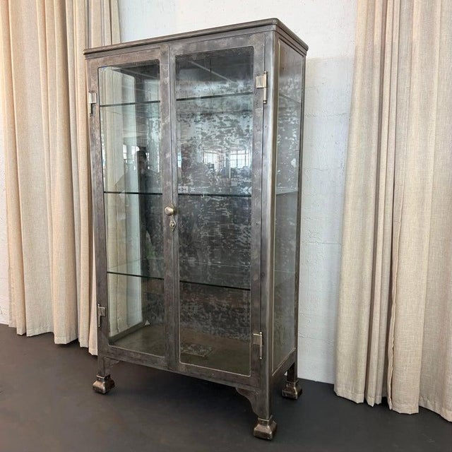 This monumental antique industrial apothecary vitrine cabinet seamlessly bridges the gap between historical utilitarianism...