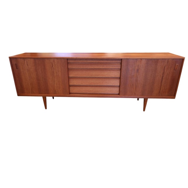 A fantastically beautiful Danish sideboard in golden brown teak, with generous storage and an elegant classic, timeless...
