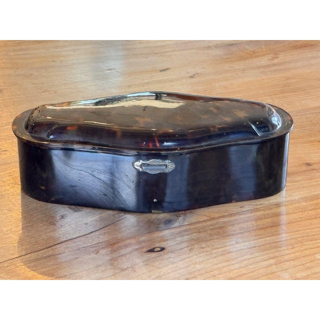 Vintage French box with gently serpentine sides and a raised, molded lid, showing a mottled pattern of honey, amber and...