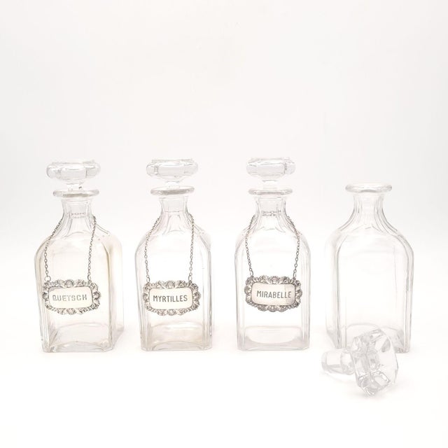 A set of four vintage decanters with three labels that read "Quetsch", "Myrtilles", "Mirabelle", France circa 1920.