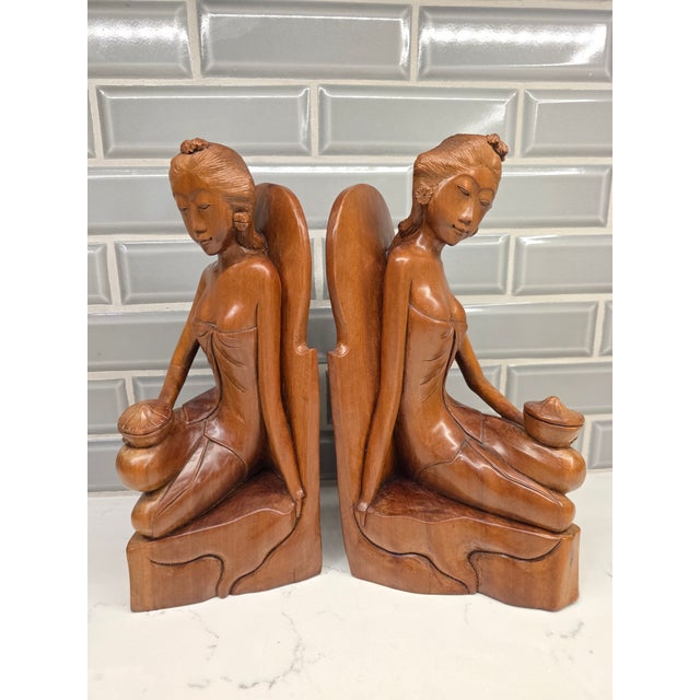 An extraordinary, investment-grade pair of matching mid-century Balinese Art Deco bookends depicting seated maidens...