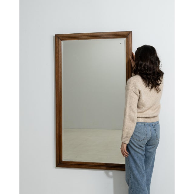 A 20th century French wall mirror presented within a substantial wooden frame. The rectangular form is defined by clean...