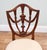 An elegant pair of dining chairs in the Hepplewhite style Each shield-shaped back is decorated with carved swags, a turned...