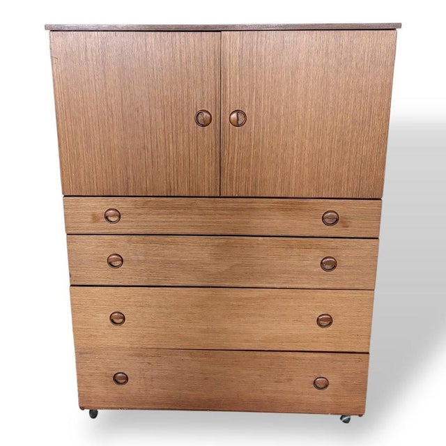 A classic mid-century tallboy cabinet by Schreiber, featuring a beautifully grained teak finish with contrasting darker...