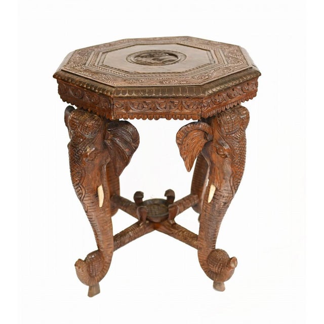 A fine Burmese elephant table heavily carved with a hexagonal top supported by four elephants with simulated wooden ivory...