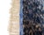 A rug of quiet contrast — where deep, textured charcoal dissolves into a crisp diamond lattice of ocean and sky blue. The...