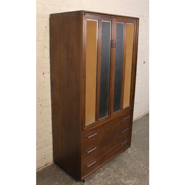 Mid-century modern armoire style cabinet by Lane Furniture. This solid unit is made with walnut grain and accenting chrome...