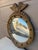 A gorgeous Federal or Regency style convex bullseye wall mirror featuring a carved eagle with open wings standing on olive...