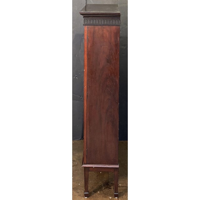 A fine English locking two-door bookcase of mahogany from the Edwardian era, featuring a moulded cornice top with a...