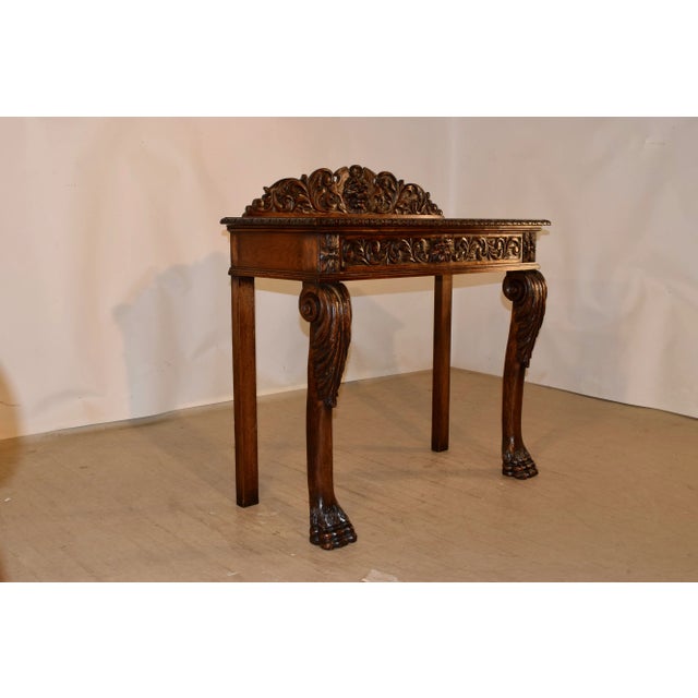 19th century oak console table from England with a stately hand carved decorated backsplash which has a central shield...