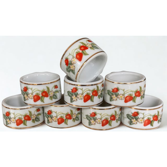 Here is a set of eight vintage fine white porcelain napkin rings with strawberry motif and 22K gold accent border. Round...