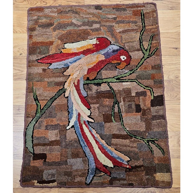 Vintage American hand hooked pictorial rug in a wonderful depiction of a parrot on a tree branch. The rug has a delightful...