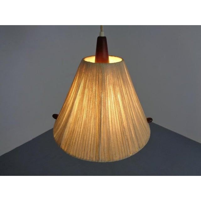 Ceiling lamp from Temde made of teak and sisal/raffia. The length of the lamp can be adjusted as desired using the pull...