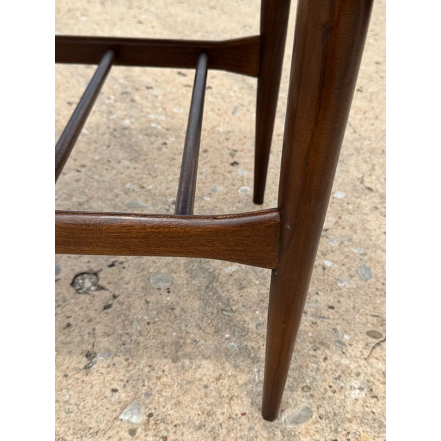 Mid-century modern walnut side table by Bassett, featuring a subtly bowed top, clean lines, and tapered legs. The open...