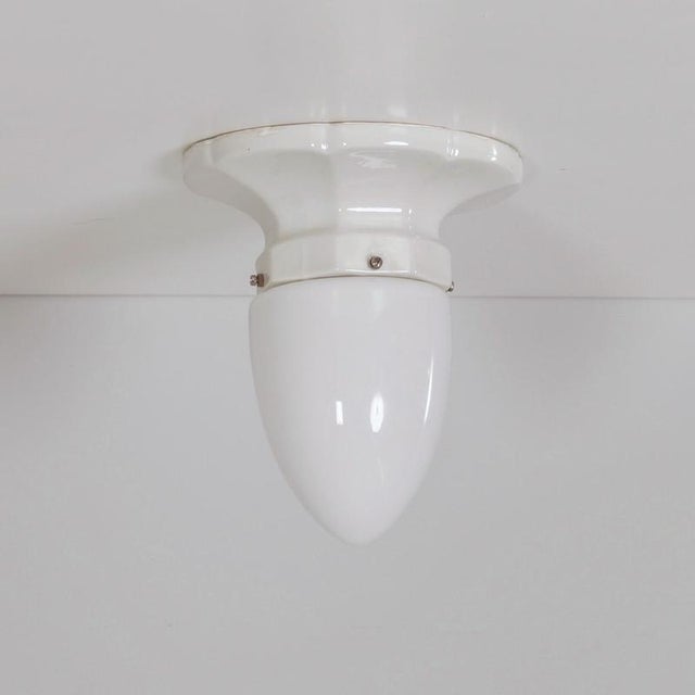 Art deco ceiling light from the 1930s with a porcelain mount and an opaline cone-shaped shade. The combination of white...