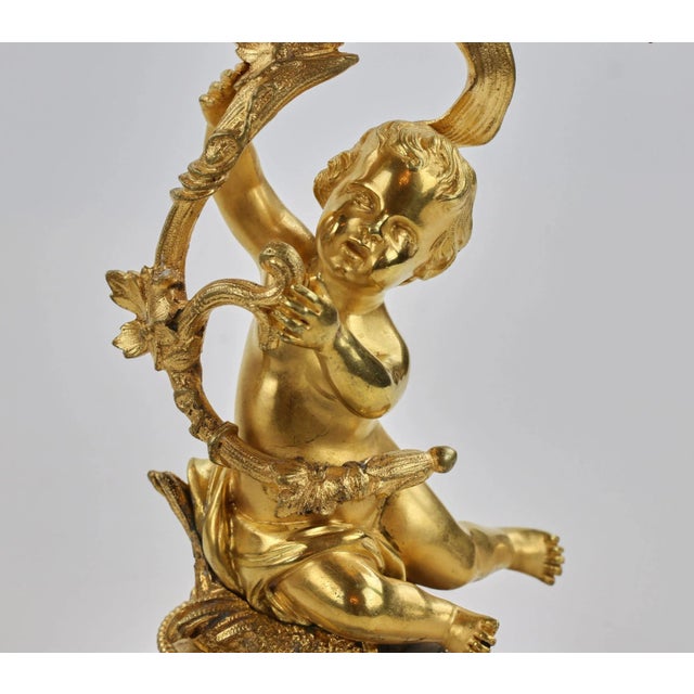 Mantel clock "allegories of painting" of gilded bronze with paired candlesticks and porcelain panels. A rocking...