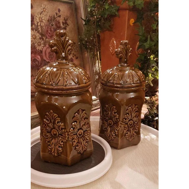 Set of 2 Fleur De Lis Ceramic Carved Urns With Lids, High gloss brown with carvings on all sides. Tall lid with Fleur De...