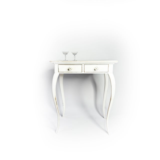 This graceful console table, finished in soft white, features two drawers and elegantly curved legs. The subtle patina and...