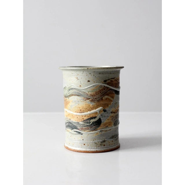 Vintage studio pottery vase featuring a hand-crafted ceramic form with a layered glaze in gray, sage green, tan, and white...