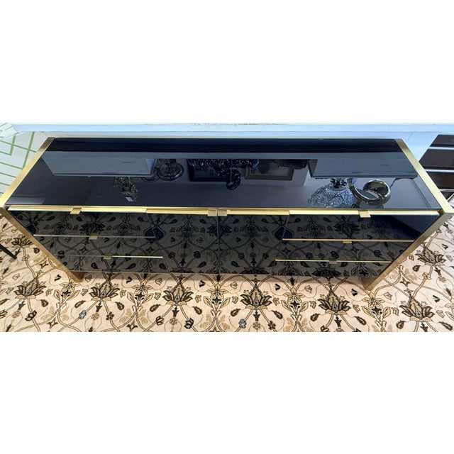 Vintage Ello black and gold dresser/credenza with glossy black fronts framed in warm brass-tone trim, offering a long, low...