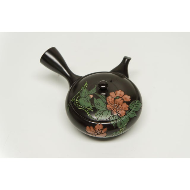 A small side handled Japanese stoneware tea pot featuring cherry blossoms design. This Tokoname teapot is characterized by...