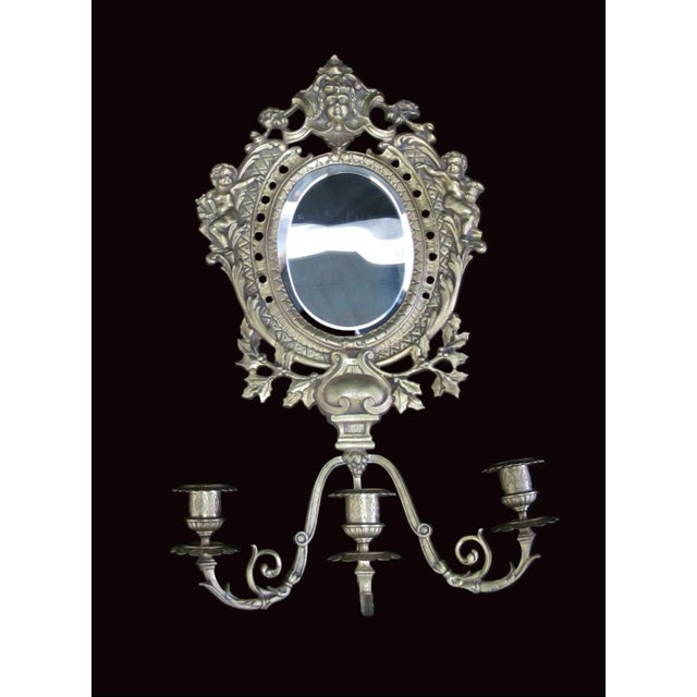 Opulent 19th century cast brass mirror and candelabra. Lavishly detailed gold brass bezeled mirror showing cherubs at each...