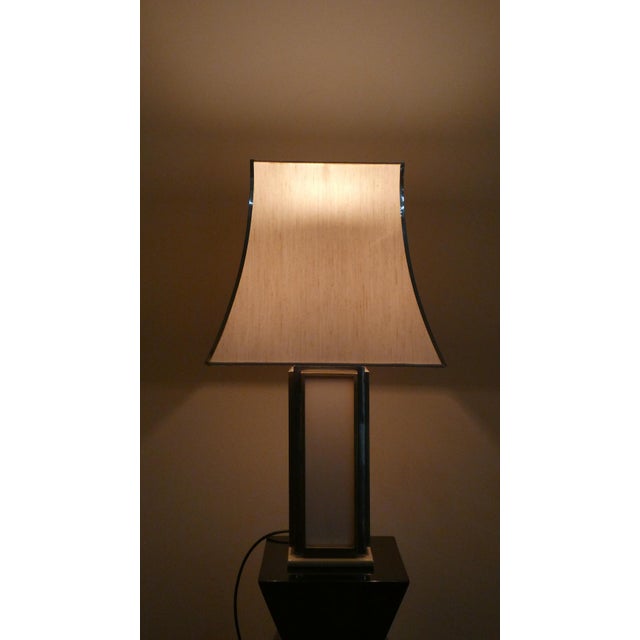 A beautiful table lamp, crafted from a brass and steel lattice frame. It features cream-colored acrylic glass panels and a...