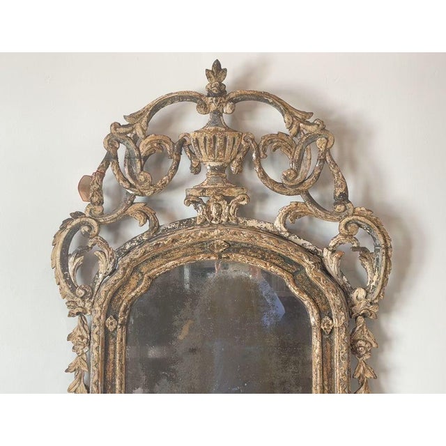 An exceptional 18th century Italian Rococo mirror, exquisitely hand-carved in wood and retaining its original parcel-gilt...