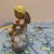 This charming vintage figurine features a whimsical cherub musician delicately perched on a puffy white cloud.