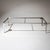 Rectangular coffee table in stainless steel with sculptural cut-out legs and a smoked glass top. The guarantee label is...
