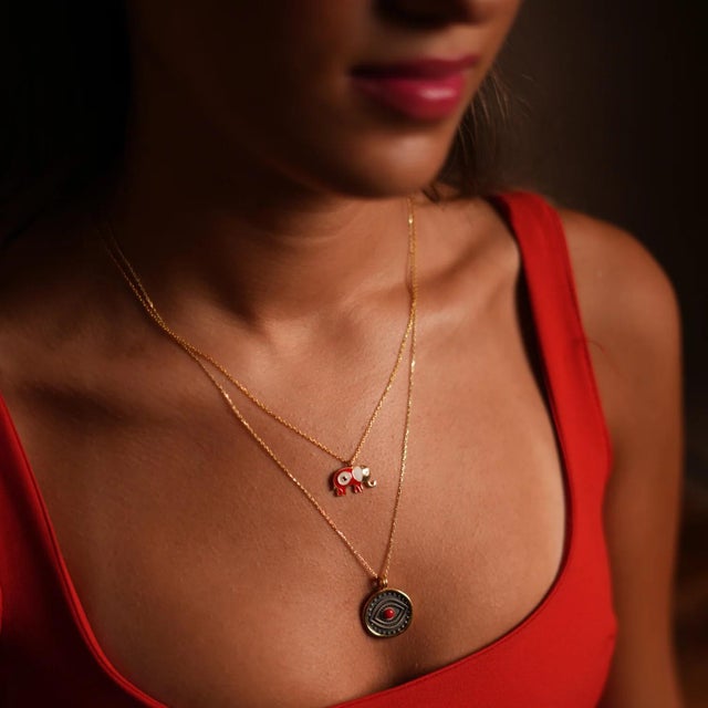 Bring both protection and luck into your life with the Wishful Elephant & Red Enamel Evil Eye Pendant Gold Chain Necklace....