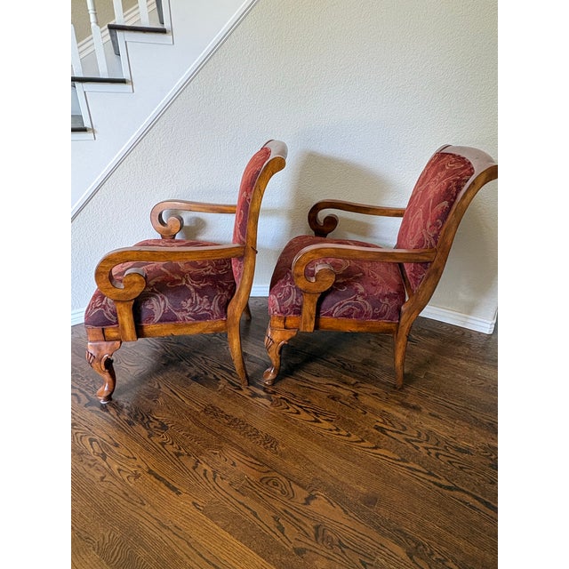 A striking pair of traditional upholstered accent chairs by Powell, featuring richly patterned burgundy tapestry...