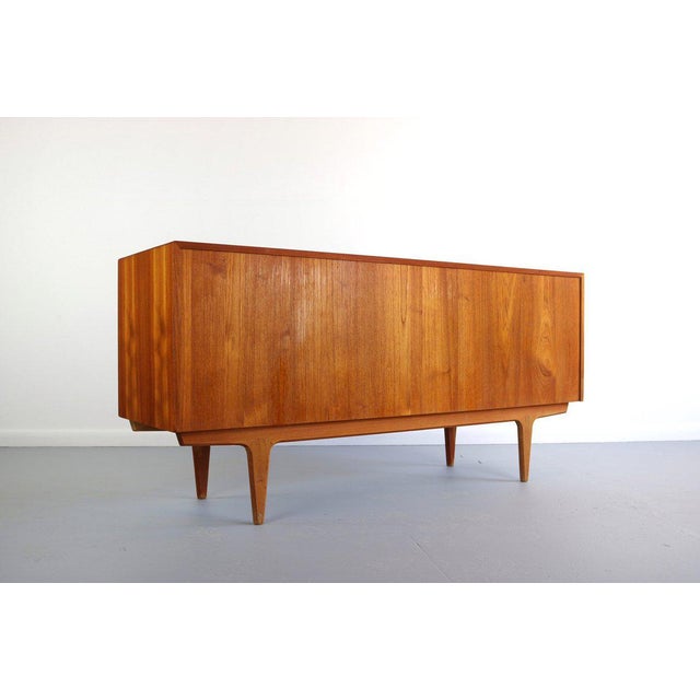 1970's teak sideboard by Bernhard Pedersen. The two tambour fronted doors slide open to reveal three central drawers which...
