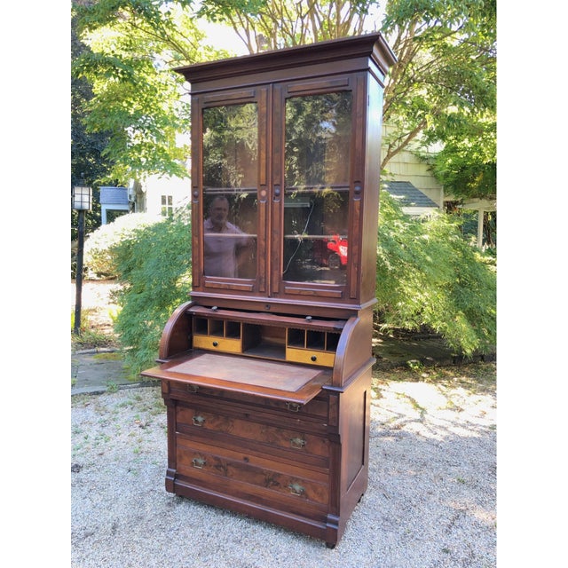 An 1880s era Victorian period Walnut cylinder roll top secretary desk and bookcase with matched burl wood panels, a pull-...
