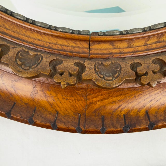 Beautiful antique round oak mirror featuring a compound serpentine profile embellished with hand carved details. An...