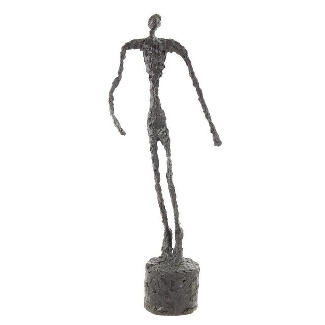 Modern dark patinated bronze sculpture depicting a standing male figure in motion, inspired by mid-20th-century figurative...