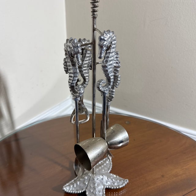 A nautical-themed vintage silver-tone metal barware tool set featuring detailed seahorse handles and a textured starfish...