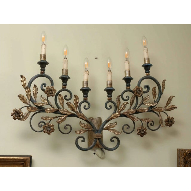 Representative wall lamp with florally composed decor, made of metal and artistically conceived in the spirit of...