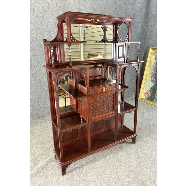 This circa 1885 mahogany display stand étagère features intricate Eastlake and Aesthetic Movement–style carving, mirrored...