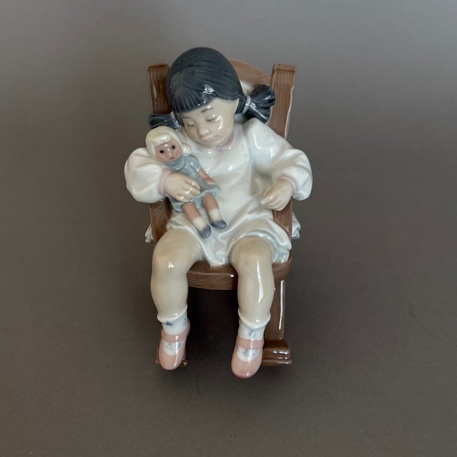 This adorable girl is rocking her baby doll but has fallen asleep herself