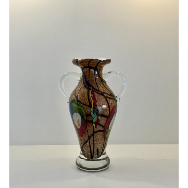 A beautifully illustrated vintage glass vase in amphora-style. A gold-colored amphora-shaped base topped with the first...
