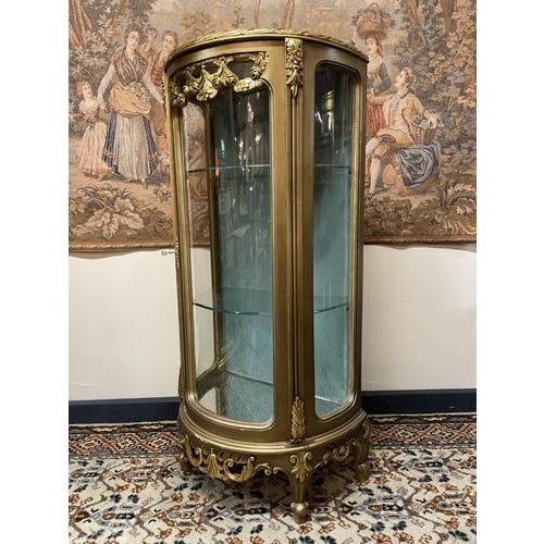 A beautifully crafted Louis XV style display cabinet, featuring a graceful demilune shape and a finely carved gilt-wood...