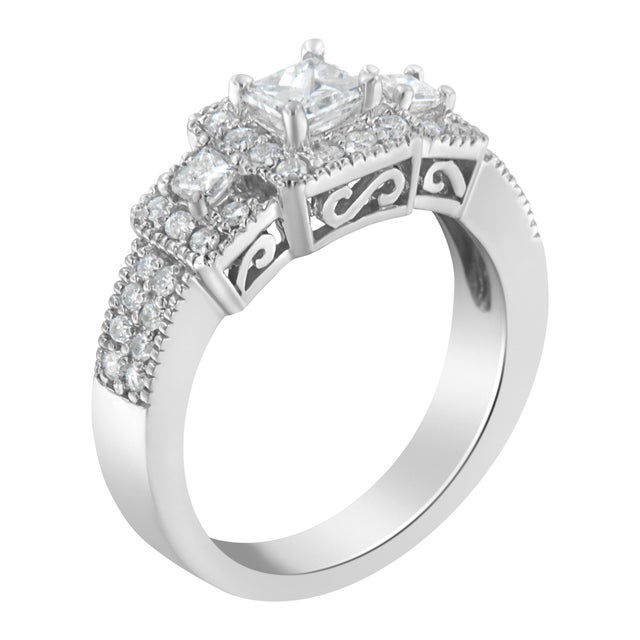 A 14 karat white gold three-stone diamond engagement ring that features three princess cut diamonds surrounded by a halo...
