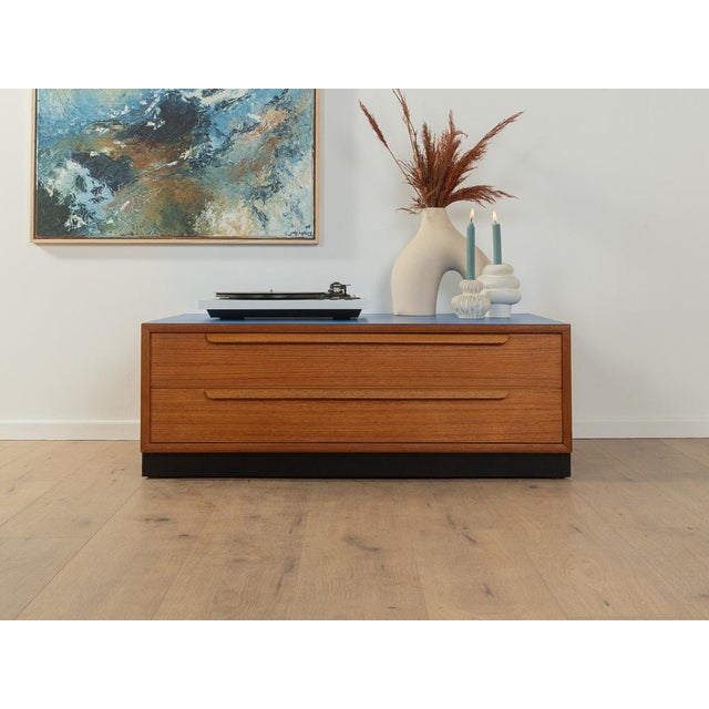 Classic chest of drawers from the 1960s. The body is made of teak veneer with two drawers and a black contrasting base....