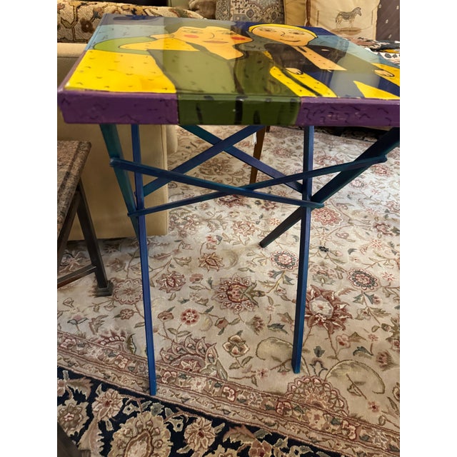A whimsical one-of-a-kind hand-painted accent table featuring a charming portrait scene in bold saturated hues of cobalt...
