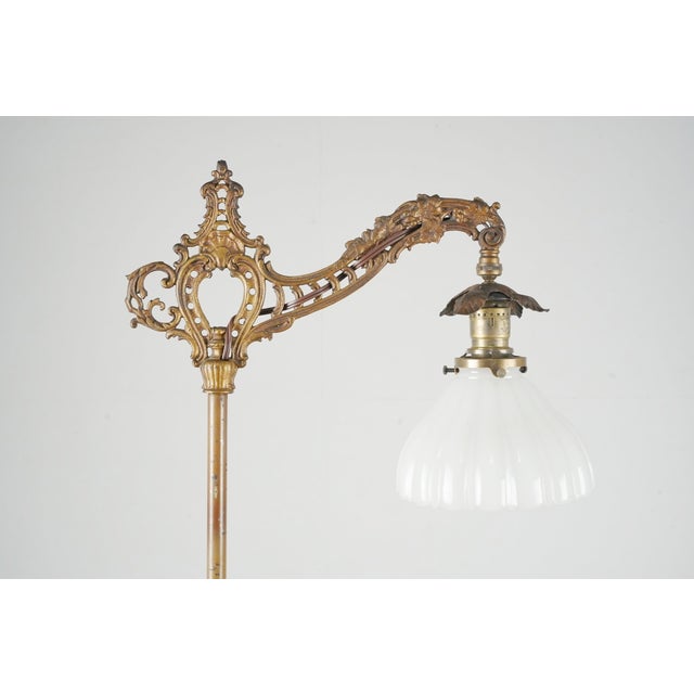 Victorian style bridge arm floor lamp made of brass plated cast iron and steel with a fluted milk glass shade. It features...
