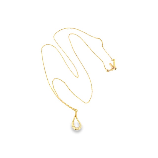 An 18k gold pendant necklace by Elsa Peretti for Tiffany & Co. The design features a sleek, teardrop-shaped pendant. The...