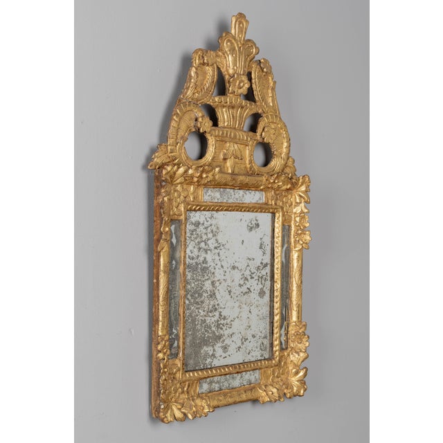 An 18th century French Regence style giltwood parclose mirror with large boldly carved sculptural crest and elaborate...